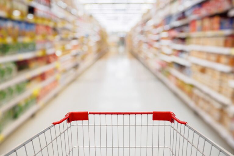 Shopping cart view in Supermarket aisle with product shelves abstract blur defocused background