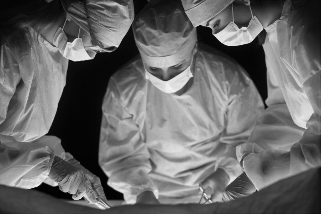 Medical team performing operation. Group of surgeon at work in operating theatre toned in blue