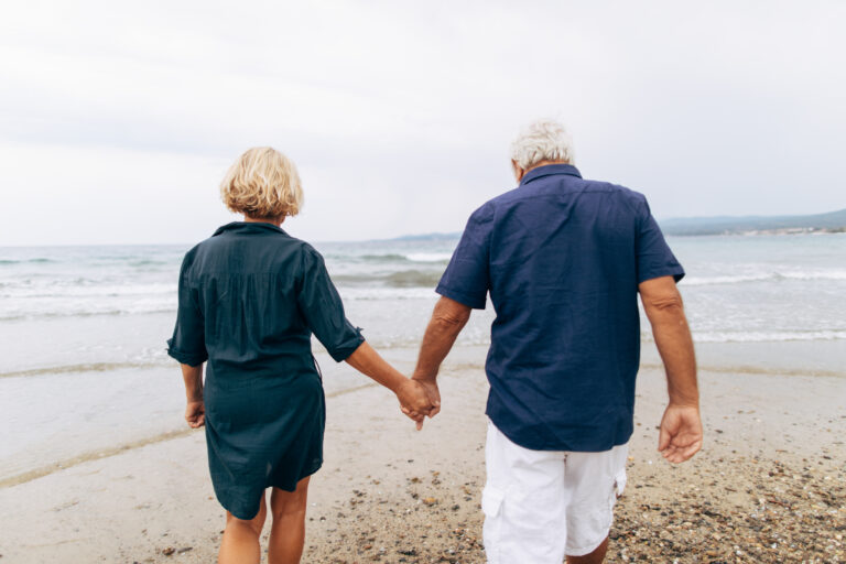 Photo of senior couple having a romantic walk by the sea while holding hands